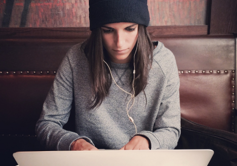 Una mujer jóven escribiendo en un ordenador portátil